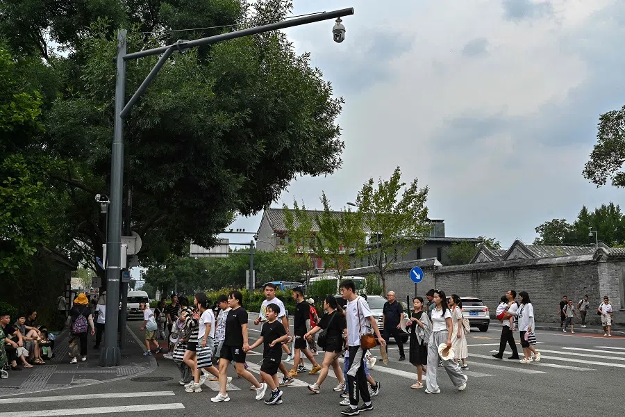 People walk along Huguosi Street, Xicheng district, in Beijing, China, on 23 August 2024. (Adek Berry/AFP)