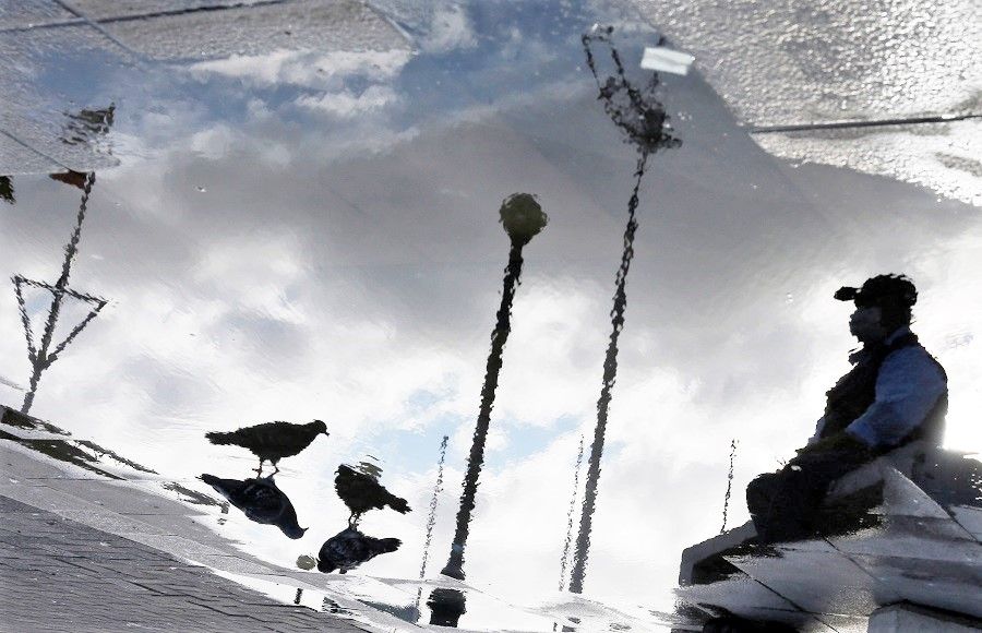 Will the global pandemic push humanity to reflect, make progress, and arrive at better global governance? In this photo taken on 27 April 2020 (rotated 180 degrees), a man is reflected on a puddle of water in a public square during the coronavirus outbreak in Valparaiso, Chile. (Rodrigo Garrido/Reuters)