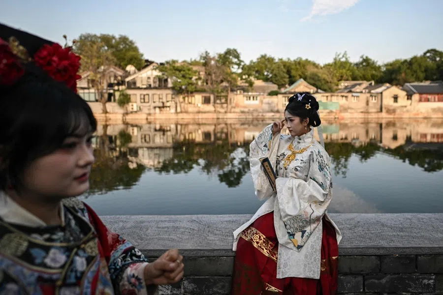 Women wearing traditional Chinese costumes pose for photographs as they visit the surroundings of the Forbidden City in Beijing on 6 October 2025. (Pedro Pardo/AFP)
