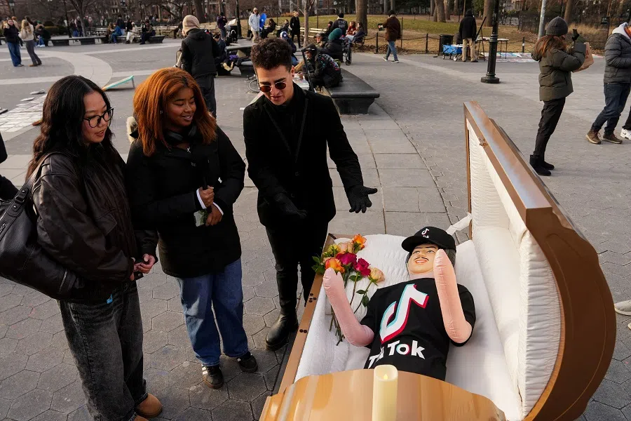 Comic Zach Sage, who posts content on TikTok, interviews people by a coffin with a blow up doll, dressed in TikTok merch, in Washington Square Park in New York City, US, on 17 January 2025.