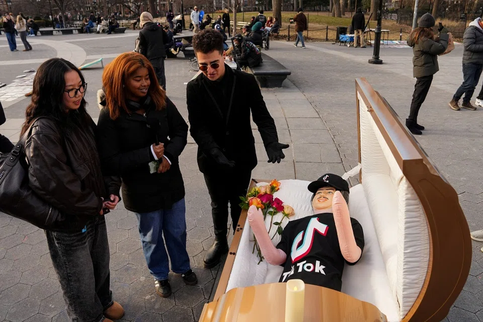 Comic Zach Sage, who posts content on TikTok, interviews people by a coffin with a blow up doll, dressed in TikTok merch, in Washington Square Park in New York City, US, on 17 January 2025. (Adam Gray/Reuters)