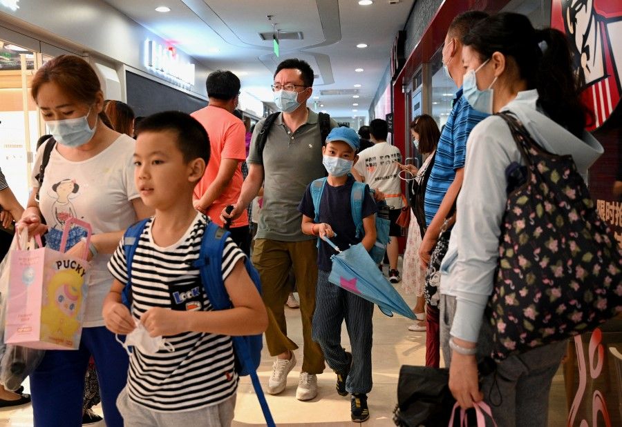 This picture taken on 29 July 2021, shows students and parents walking after attending a private after-school education in Haidan district of Beijing. (Noel Celis/AFP)