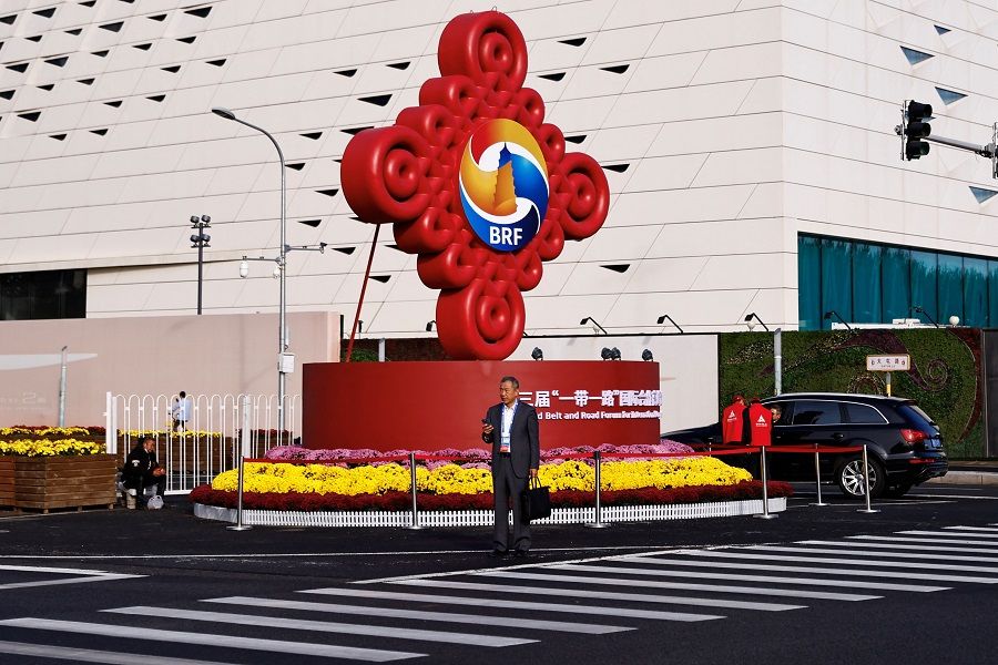 A person stands in front of a sign of the third Belt and Road Forum in Beijing, China, on 18 October 2023. (Tingshu Wang/Reuters)