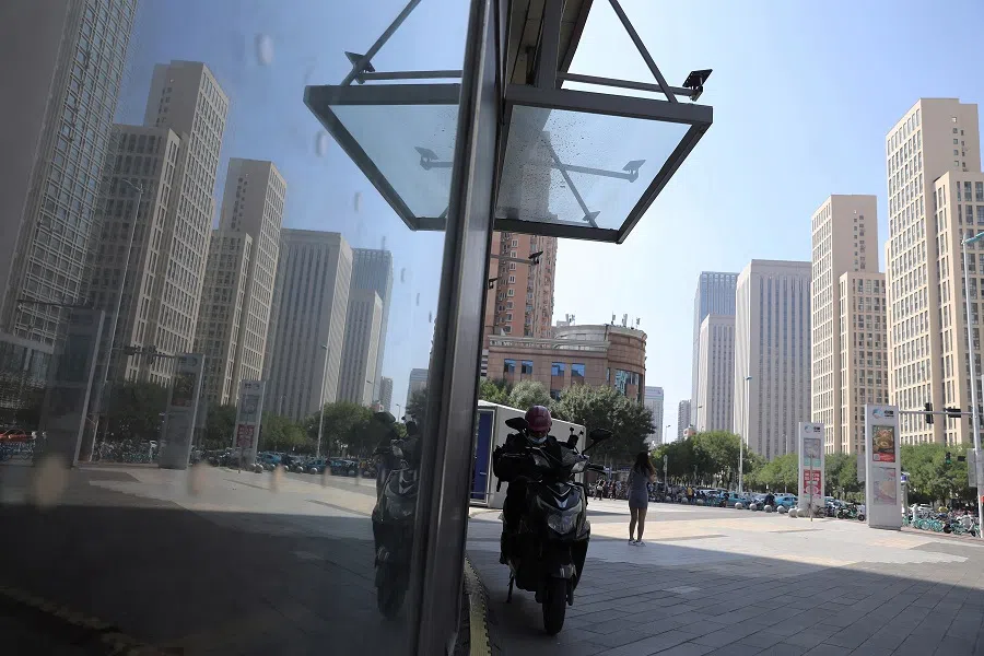 A delivery worker rests on his scooter near residential compounds in Tianjin, China, 7 September 2021. (Tingshu Wang/Reuters)