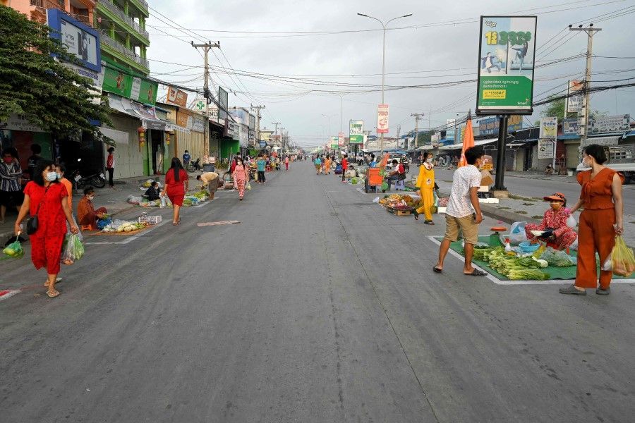 Vendors sell their goods along a street marked for social distance after markets were closed due to lockdown restrictions to halt the spiralling Covid-19 coronavirus cases in Phnom Penh on 30 April 2021. (Tang Chhin Sothy/AFP)
