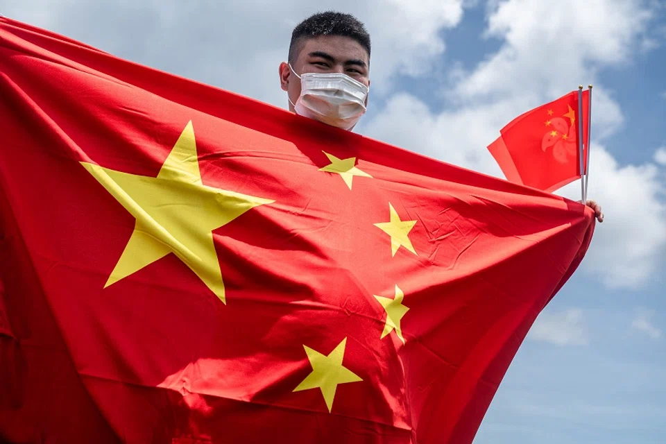 A government supporter wearing a protective mask holds Chinese and Hong Kong Special Administrative Region (HKSAR) flags to celebrate the passage of a national security law in Hong Kong, China, on 30 June 2020. (Lam Yik/Bloomberg)