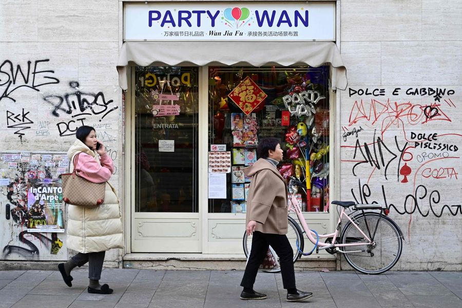 Passers-by pass by a shop in Via Paolo Sarpi, the commercial street of the Chinese district of Milan on 30 January 2020. (Miguel Medina/AFP)