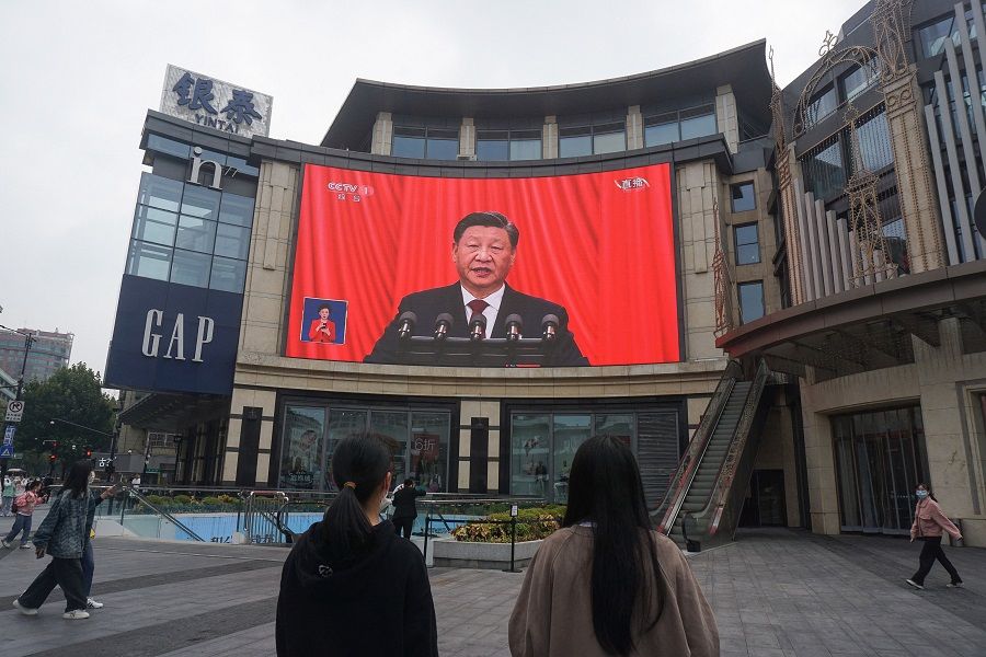 People watch an outdoor screen showing the live speech of Chinese President Xi Jinping during the opening ceremony of the 20th Party Congress in Hangzhou, Zhejiang province, China, on 16 October 2022. (AFP)