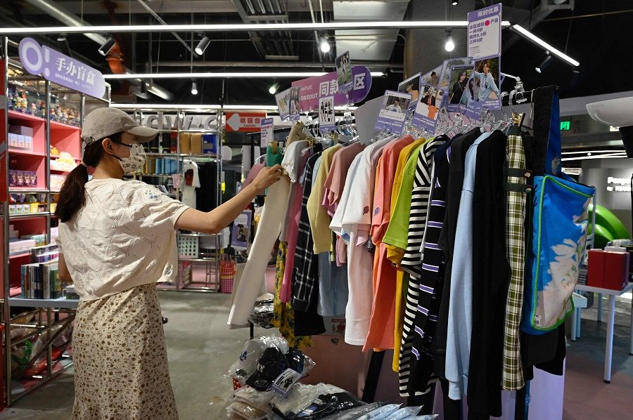 A customer browses clothing similar to those worn by celebrity idols at a fan merchandise store at a shopping mall in Beijing, China, on 2 September 2021. (Jade Gao/AFP)