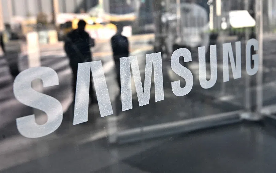 In this file photo taken on 6 April 2021, people walk past the logo of Samsung Electronics at the company's Seocho building in Seoul, South Korea. (Jung Yeon-je/AFP)