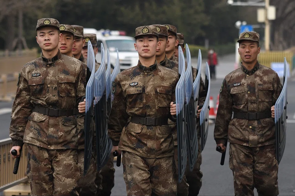 People's Liberation Army soldiers march to their barracks opposite the Great Hall of the People in Beijing on 24 February 2020. (Greg Baker/AFP)