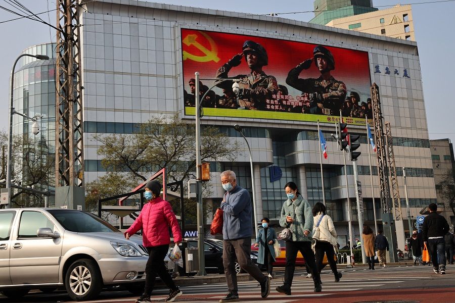 An advertisement of the People's Liberation Army overlooks a street scene on the day Chinese President Xi Jinping and his US counterpart Joe Biden hold a virtual summit, in Beijing, China, 16 November 2021. (Thomas Peter/Reuters)