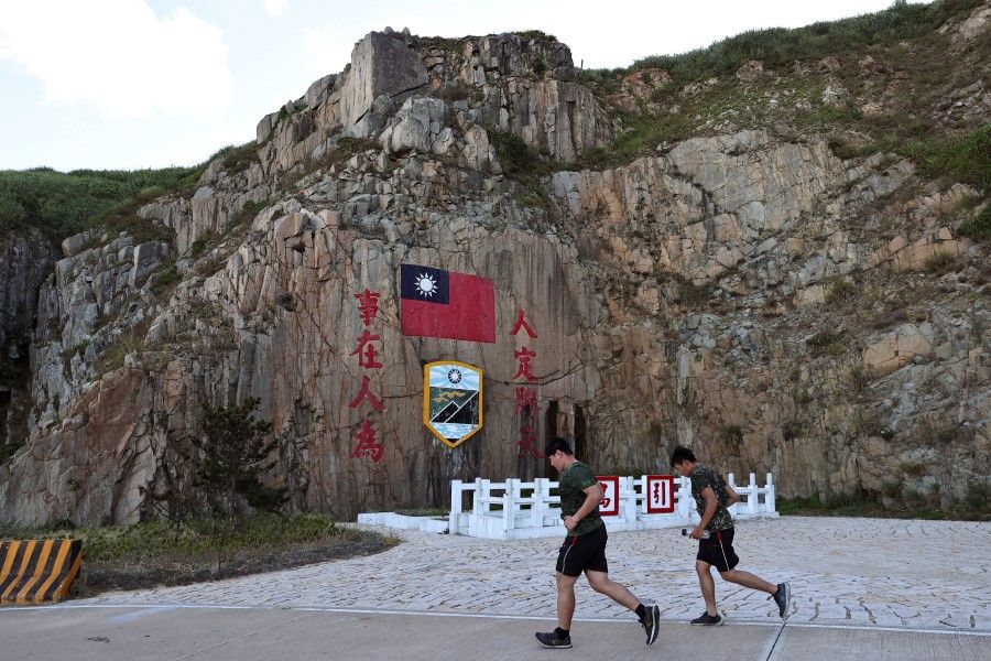Soldiers jog past a sign of the Taiwan flag on Dongyin island of Matsu archipelago in Taiwan, 15 August 2022. (Ann Wang/Reuters)