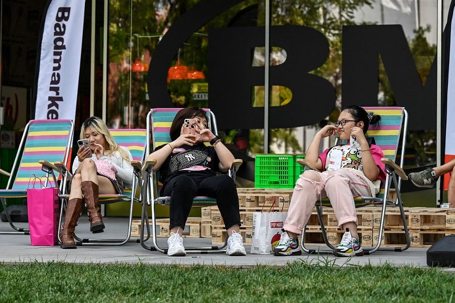 People sit on folding chairs outside a shopping mall in Beijing, China, on 20 July 2023. (Jade Gao/AFP)