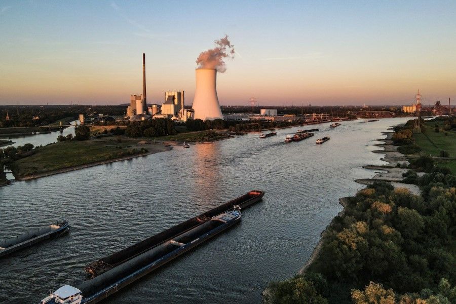 Inland motor freighters transporting coal along the Rhine River navigate low water levels while passing the Duisburg-Walsum combined heat and power plant, operated by STEAG GmbH, in the Walsum district of Duisburg, Germany, on 10 August 2022. (Ben Kilb/Bloomberg)