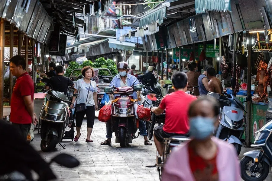 Motorists ride along a market in Haikou, China on 24 August 2026.