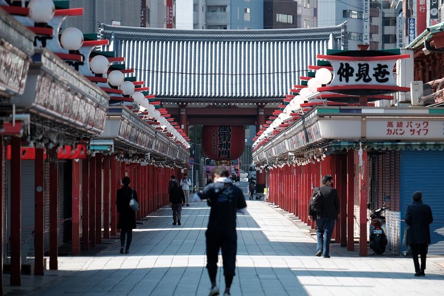 People walk past closed stores on the Nakamise shopping street leading to the Sensoji temple in the Asakusa district of Tokyo, Japan, on 25 April 2020. (Soichiro Koriyama/Bloomberg)