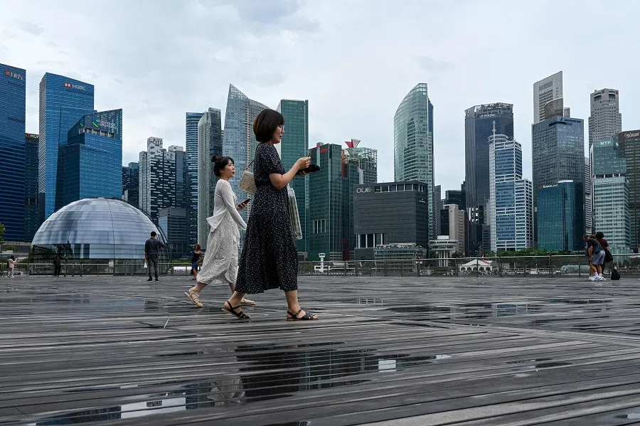 People walk on the boardwalk in front of commercial high rise buildings at Marina Bay in Singapore on 26 September 2024. (Roslan Rahman/AFP)