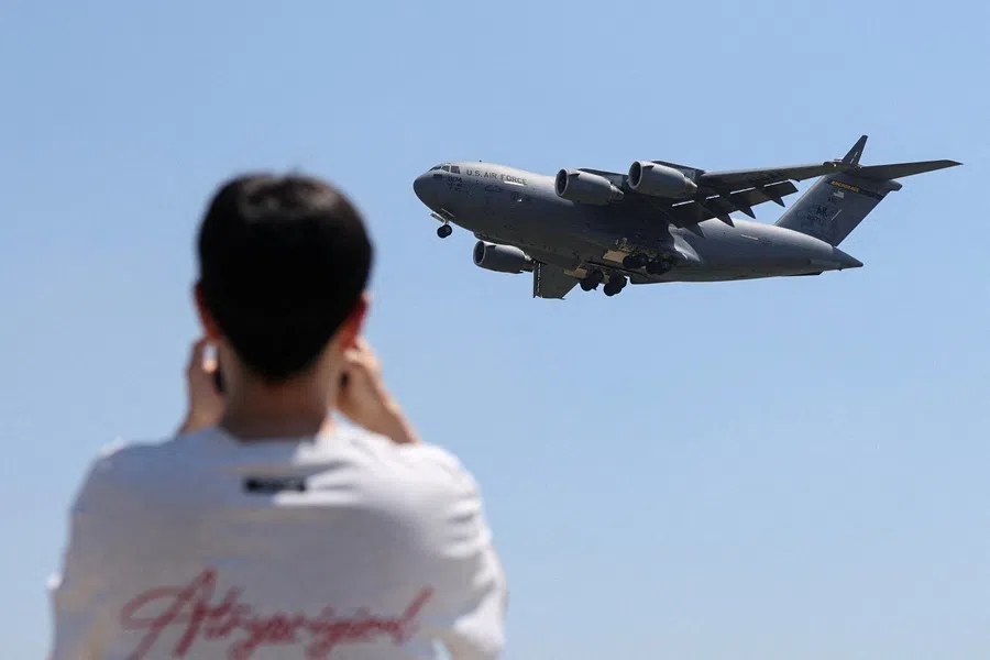 A man uses his phone as a US Air Force C-17A Globemaster III lands at Beijing Capital International Airport in Beijing, China, on 11 May 2026.