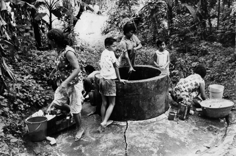 Villagers in Adam Park washing clothes near a common well. In the early 1960s, people who lived in kampungs (villages) had to draw water from common wells. (SPH Media)