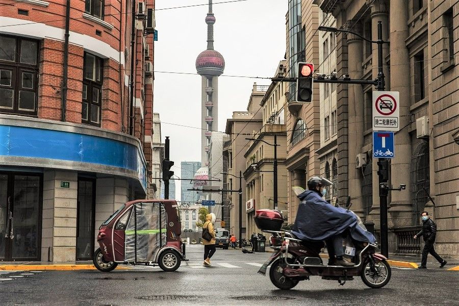 Pedestrians and motorcyclists along a road near the Bund in Shanghai, China, on 30 November 2022. (Qilai Shen/Bloomberg)
