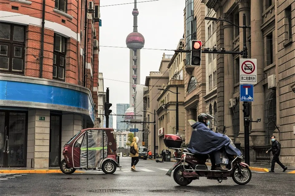 Pedestrians and motorcyclists along a road near the Bund in Shanghai, China, on 30 November 2022. (Qilai Shen/Bloomberg)