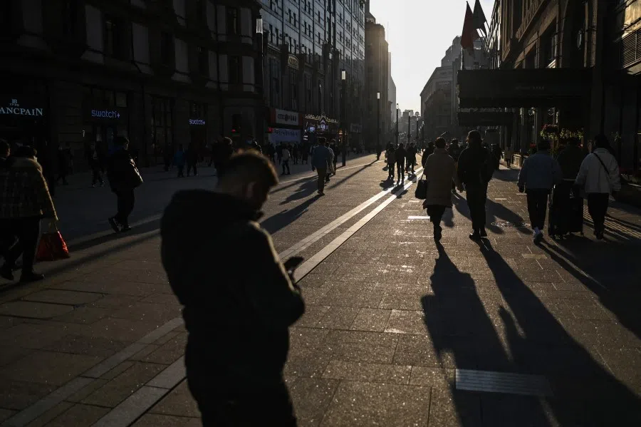 People walk on a pedestrian street on the Bund in Shanghai on 24 February 2022. (Hector Retamal/AFP)