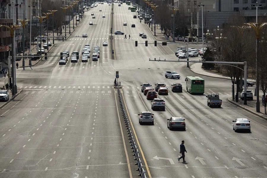 Traffic moves down the main road cutting through the city centre as a resident crosses in Hegang, China, on 1 April 2023. (Qilai Shen/Bloomberg)