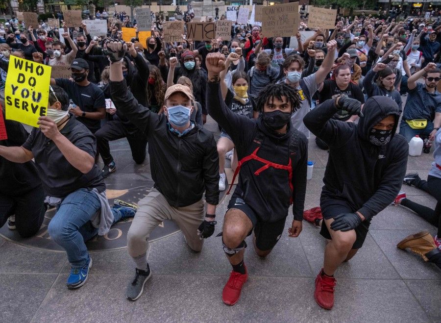Protesters kneel and raise their arms as they gather peacefully to protest the death of George Floyd at the State Capital building in downtown Columbus, Ohio, 1 June 2020. (Seth Herald/AFP)