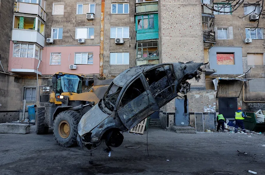 Specialists remove a burnt car in the courtyard of a damaged multi-storey residential building following recent shelling, in the course of the Russia-Ukraine conflict in Makiivka, a Russian controlled region of Ukraine, on 9 February 2025. (Alexander Ermochenko/Reuters)