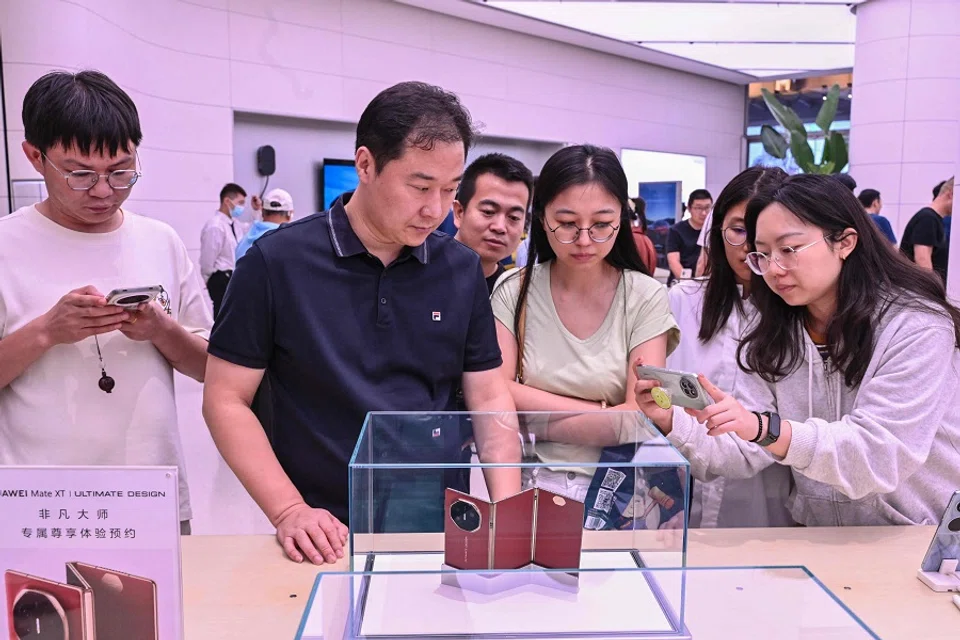 Shoppers checking out the Huawei Mate XT at a Huawei store in Beijing on 10 September 2024. Huawei on 10 September unveiled the world’s first triple-folding phone at more than three times the price of the newest iPhone, hours after its US competitor lifted the curtain on its own new handset. (Adek Berry/AFP)