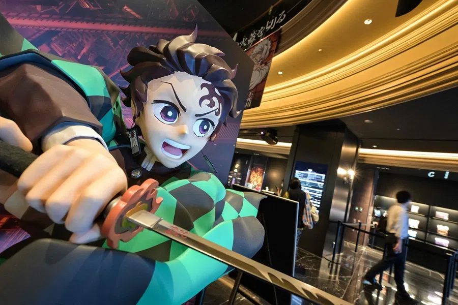 This photo taken on 9 September 2025 shows a man walking past a statue of young swordsman Tanjiro Kamado (left), the title character in the Japanese anime film Demon Slayer, on display at a cinema in the Ikebukuro area of Tokyo. (Richard A. Brooks/AFP)