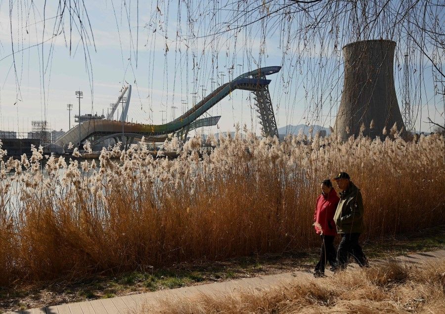 People walk near the Shougang Big Air venue, which will host the big air freestyle skiing and snow boarding competitions at the Beijing 2022 Winter Olympics, at the Shougang Park in Beijing on 7 December 2021. (Noel Celis/AFP)