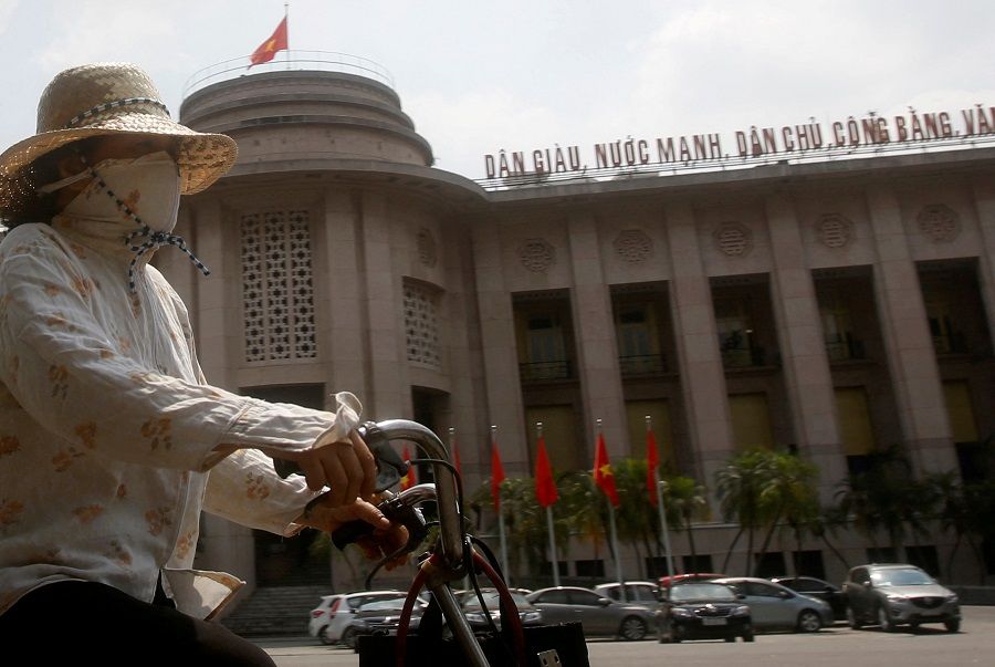A woman rides a bicycle past the building of the State Bank of Vietnam in Hanoi, 17 May 2016. (Kham/File Photo/Reuters)