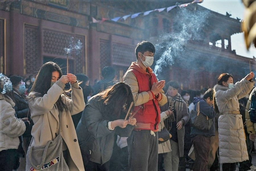 People gather to burn incense sticks and offer prayers at the Lama Temple, in Beijing, China, on 19 February 2023. (Jade Gao/AFP)