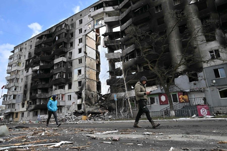 People walk past destroyed buildings in the town of Borodianka, northwest of Kyiv, Ukraine, on 4 April 2022. (Sergei Supinsky/AFP)