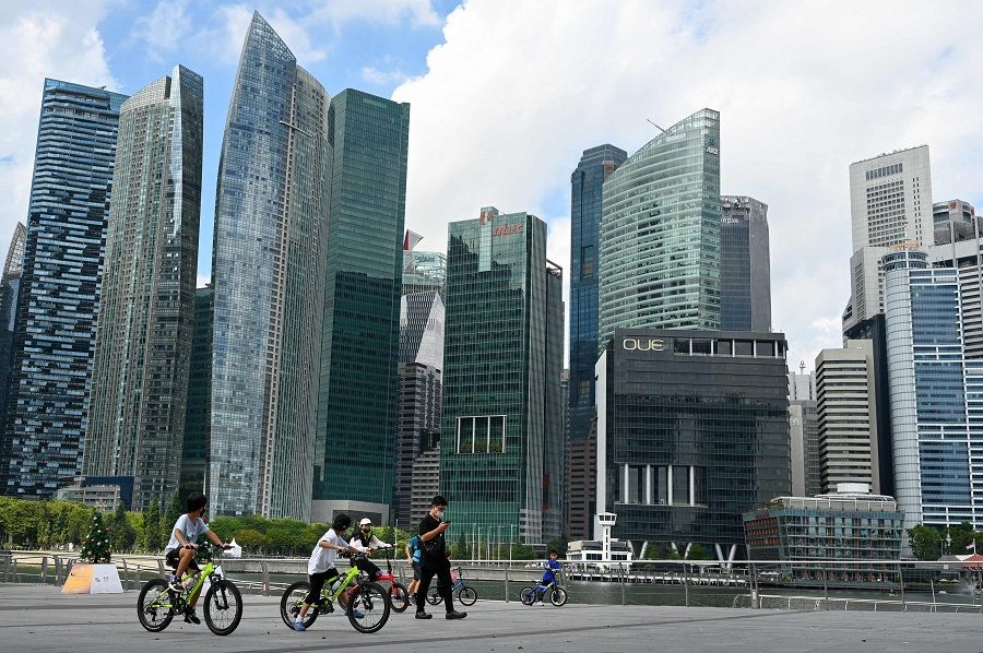 People ride bicycles along the promenade at Marina Bay in Singapore on 21 December 2021. (Roslan Rahman/AFP)