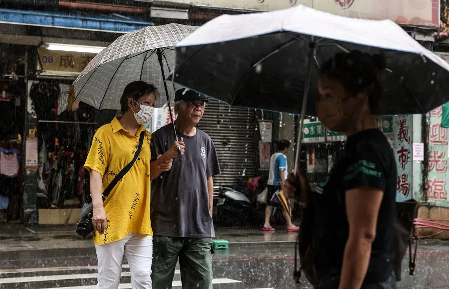People hold umbrellas while walking on the street in Keelung, Taiwan, 4 September 2023. (I-Hwa Cheng/AFP)