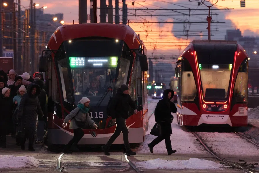 People walk out of a tram and rush to cross a street during sunrise in Saint Petersburg, Russia, on 20 February 2025. (Anton Vaganov/Reuters)
