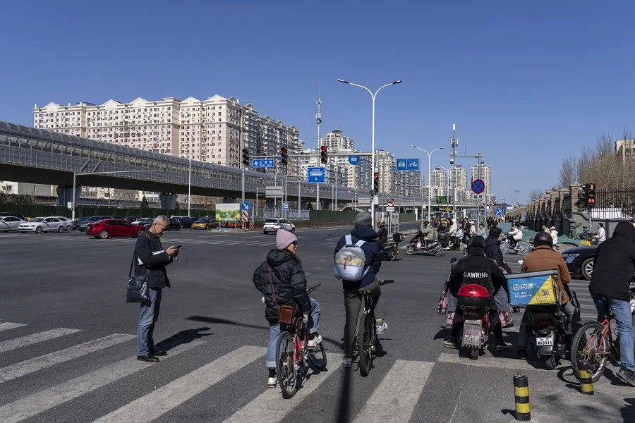 Riders and cyclists at a road near residential buildings in Beijing, China, on 3 March 2024. (Qilai Shen/Bloomberg)