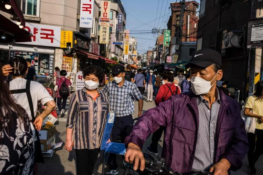 Pedestrians walk past street market stalls in Seoul on 1 October 2021. (Anthony Wallace/AFP)