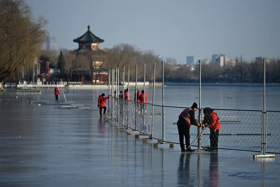 Workers install fencing for a ice rink to be opened on a frozen lake in Beijing on 13 January 2026. (Wang Zhao/AFP)