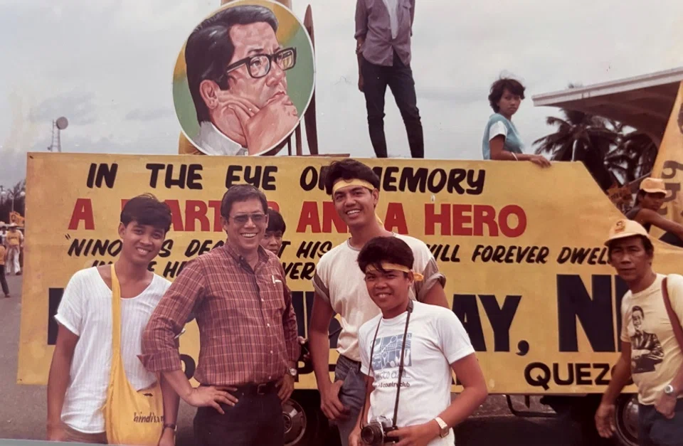 The younger brother of the assassinated Benigno Aquino Jr in front of a political banner commemorating the late senator, 1986.
