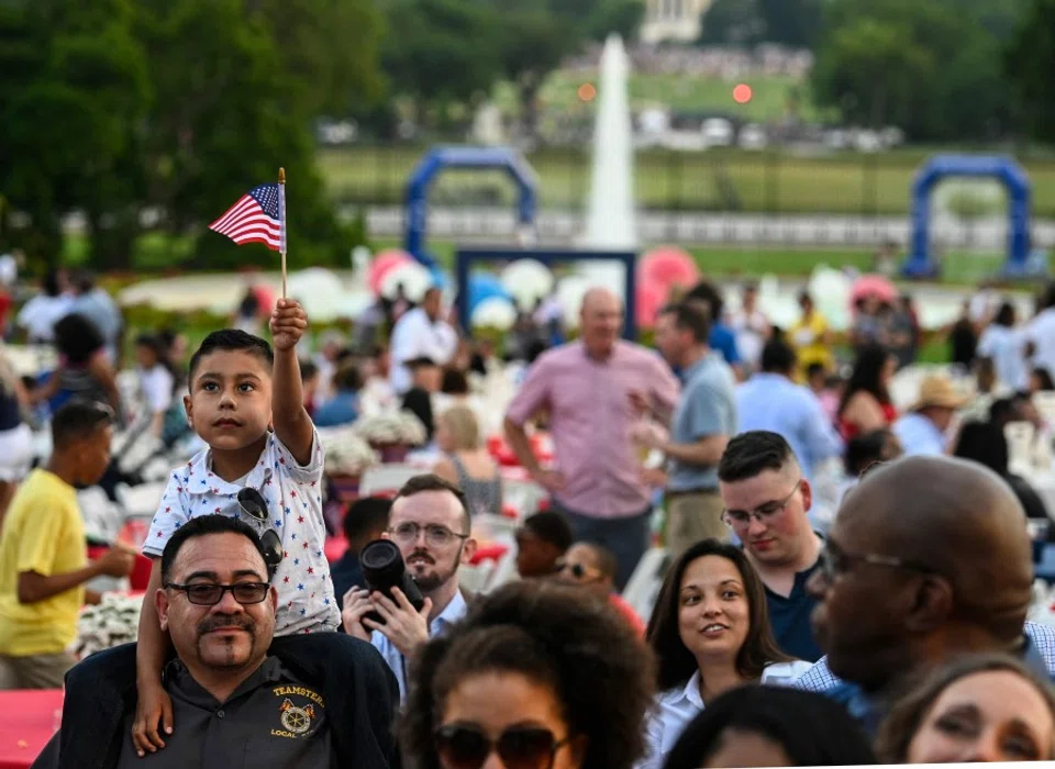 A boy holds up a US flag as guests attend Independence Day celebrations at the White House in Washington, DC, 4 July 2021. (Andrew Caballero-Reynolds/AFP)