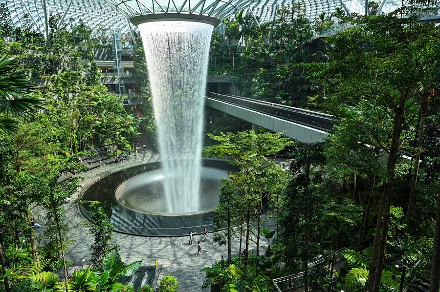 People walk around the rain vortex at Jewel Changi Airport in Singapore on 23 June 2021. (Roslan Rahman/AFP)