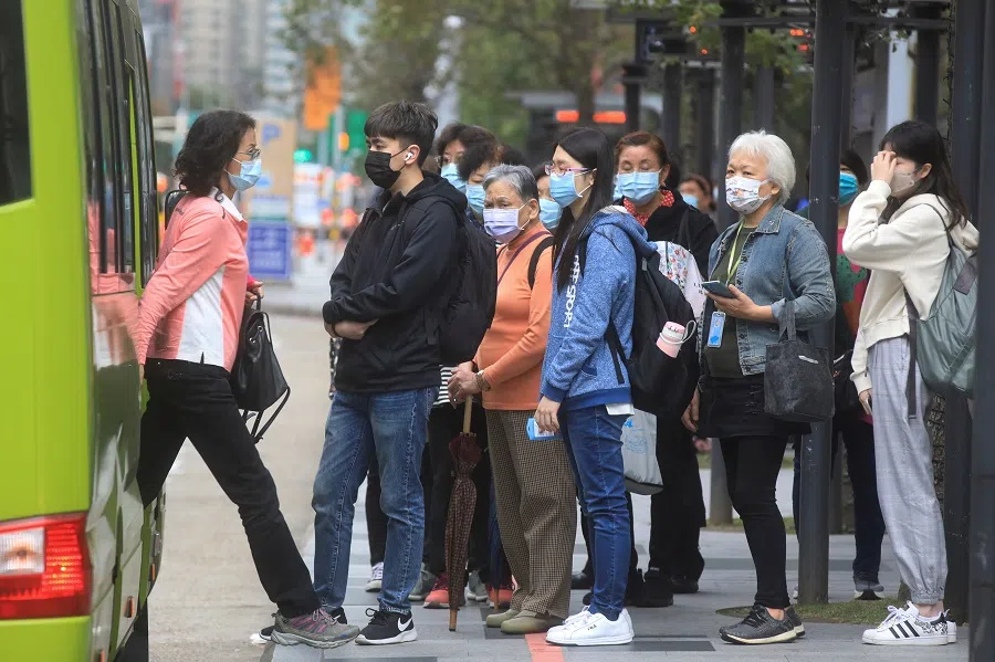 People wearing masks wait at a bus stop, in Taipei, Taiwan, 30 November 2021. (I-Hwa Cheng/Reuters)