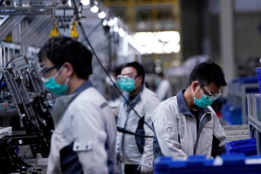 Employees wearing face masks work on a car seat assembly line at a factory in Shanghai, China, 24 February 2020. (Aly Song/Reuters)