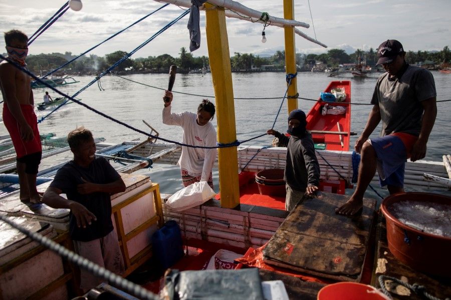 Five years after South China Sea ruling, China's presence around the Philippines grows. Filipino fishermen prepare to unload fish after arriving from a week-long trip to the disputed Scarborough Shoal, in Infanta, Pangasinan province, Philippines, 6 July 2021. (Eloisa Lopez/Reuters)