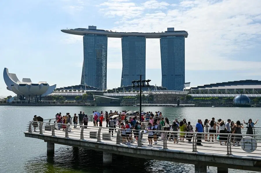 People take pictures at the Marina Bay waterfront in Singapore on 24 March 2026. (Roslan Rahman/AFP)