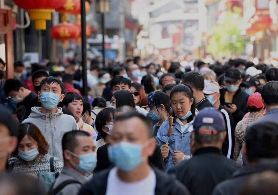 People walk along Qianmen Street, a popular pedestrianised traditional street with shops and restaurants in Beijing on 2 May 2021. (Photo by Noel Celis / AFP)